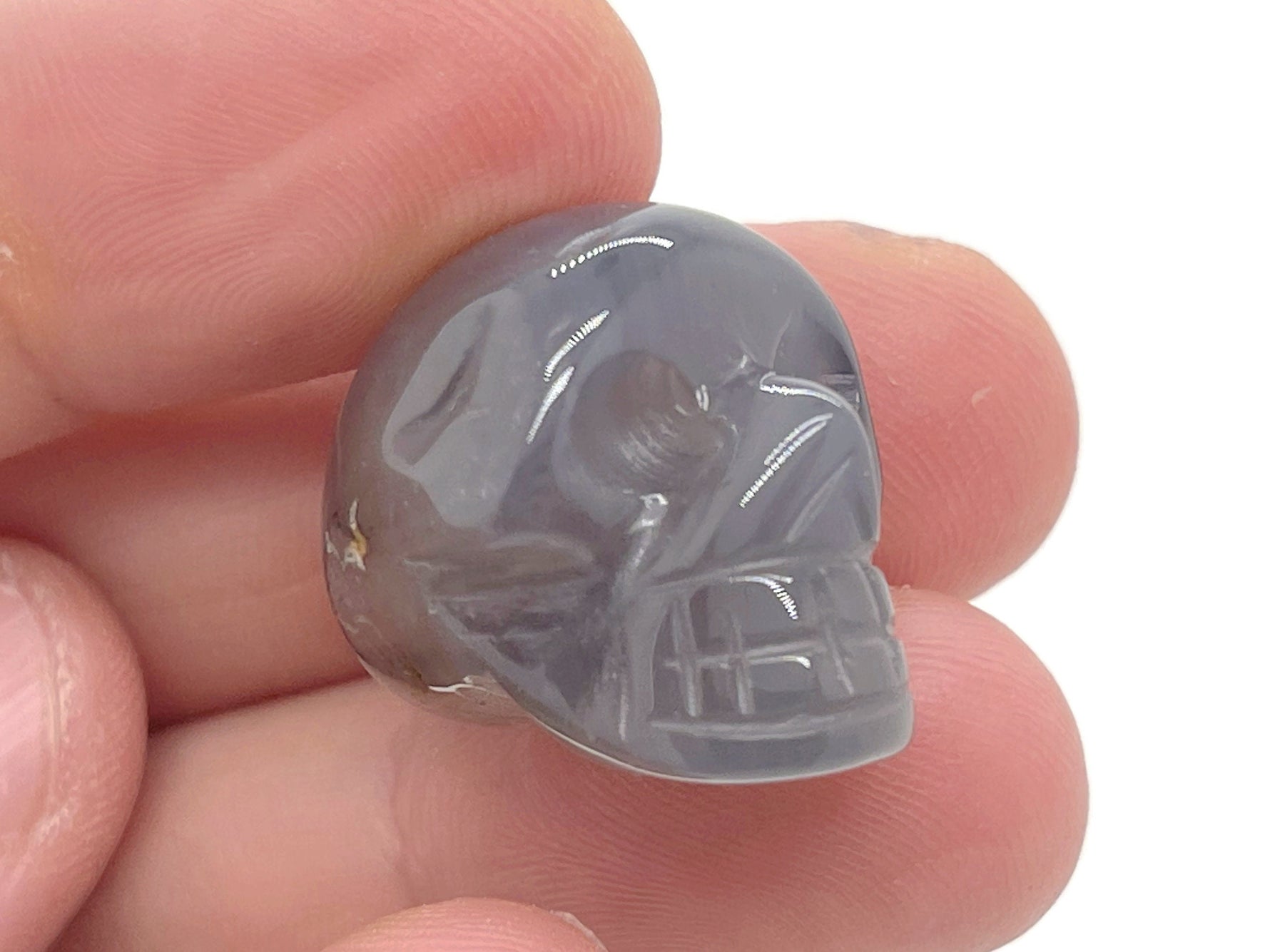 Gray agate skull carved gemstone, 25mm, with detailed features and smooth surface, showcasing a unique gemstone carving from GemstoneGO.