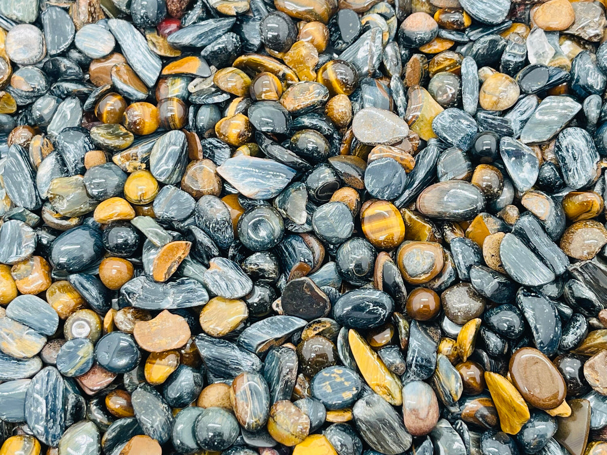 Blue tiger eye crystal chips, semi-tumbled 5-7mm gemstones from GemstoneGO, arranged in a pile for bulk use.