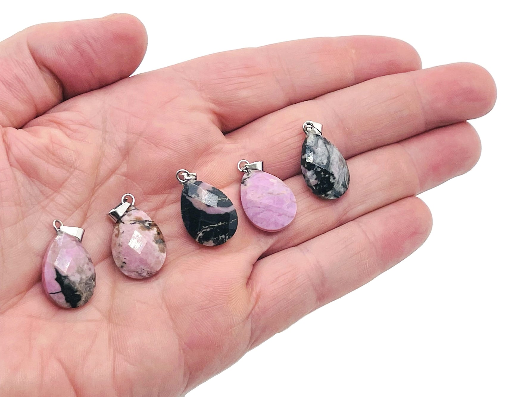 Rhodonite crystal pendant, 20mm gemstone for jewelry making from GemstoneGO, shown with polished pink and black matrix details.