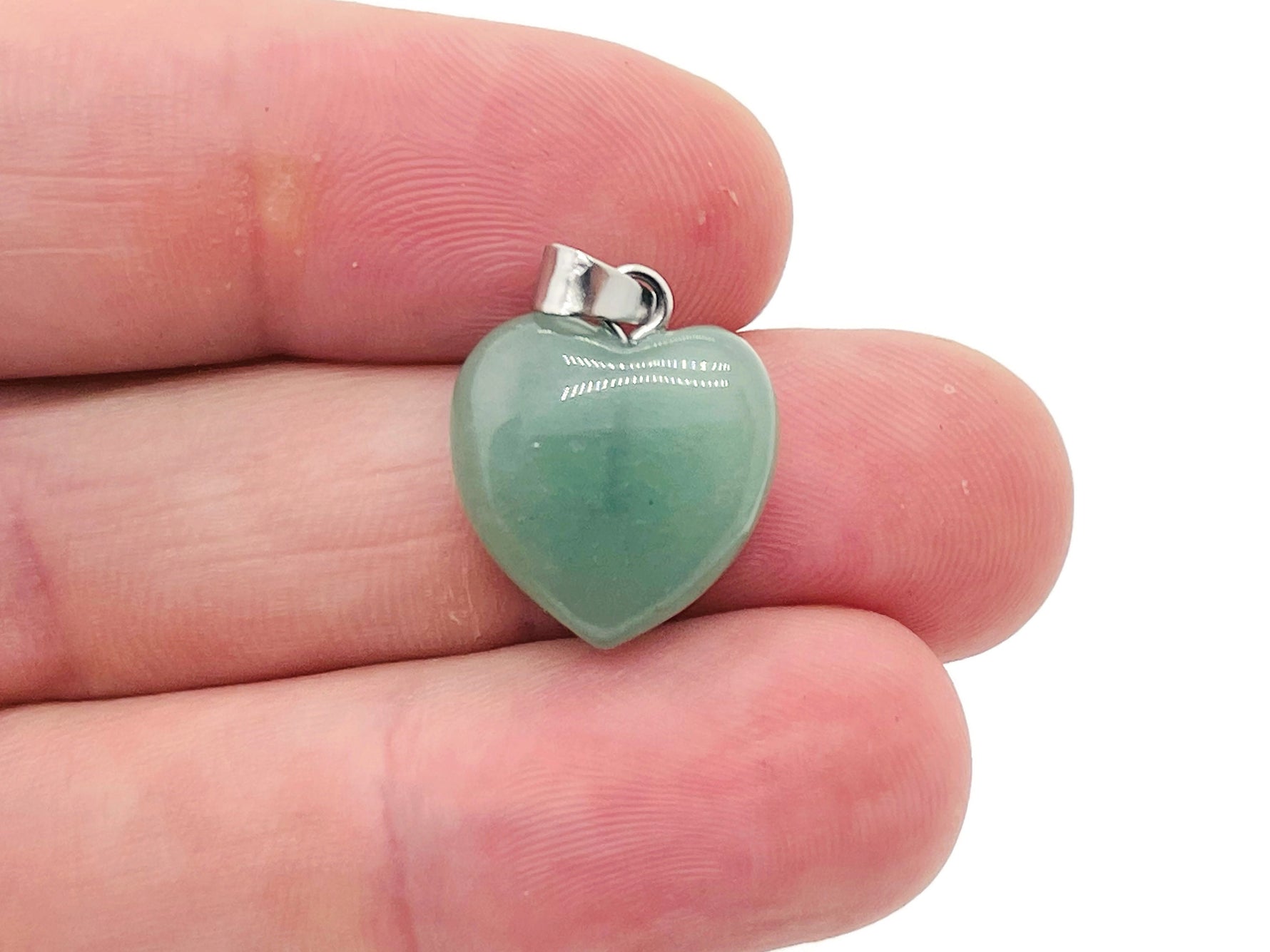 A close-up of a GemstoneGO aventurine heart pendant, a mini crystal jewelry piece with a polished green gemstone heart.