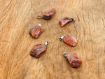 Carnelian crystal pendant with polished oval shape and silver-tone bail from GemstoneGO, showcasing vibrant orange gemstone.