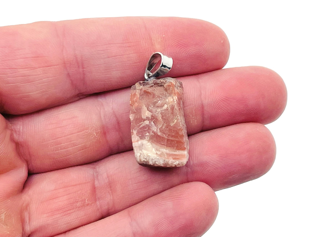 Carnelian crystal pendant featuring a polished orange gemstone on a silver chain, displayed against a neutral background.