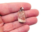Carnelian crystal pendant featuring a polished orange gemstone on a silver chain, displayed against a neutral background.