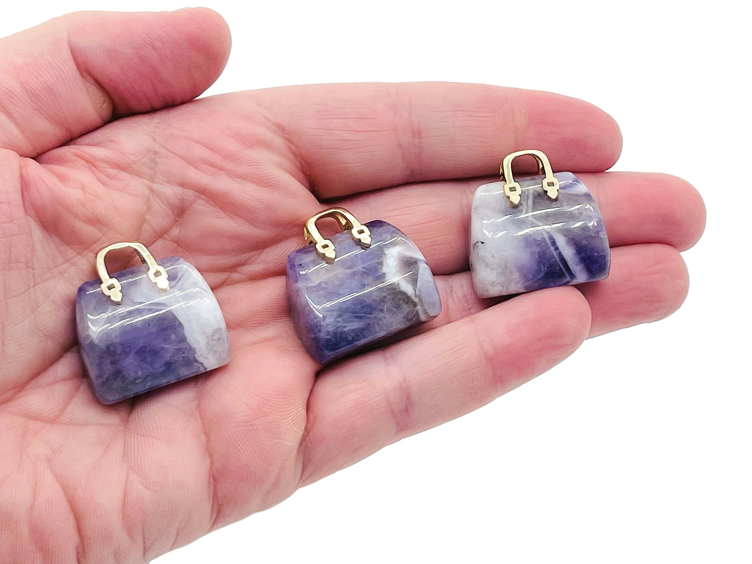 Amethyst crystal handbag pendant with carved gemstone design, showcasing a purple gemstone with intricate detailing and a silver bail.