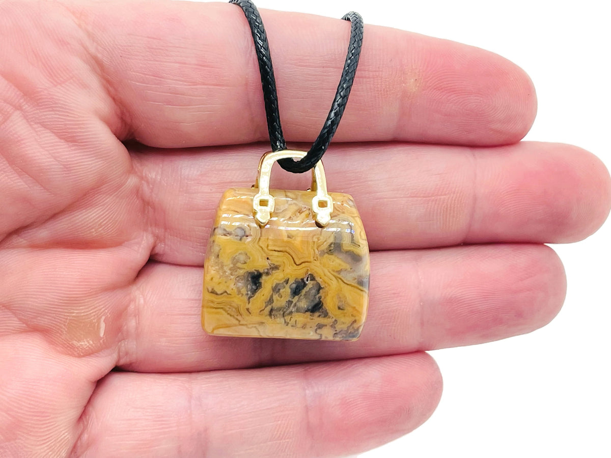 Crazy Lace Agate crystal carved as a purse-shaped gemstone pendant with intricate patterns, designed as a stylish handbag accessory.