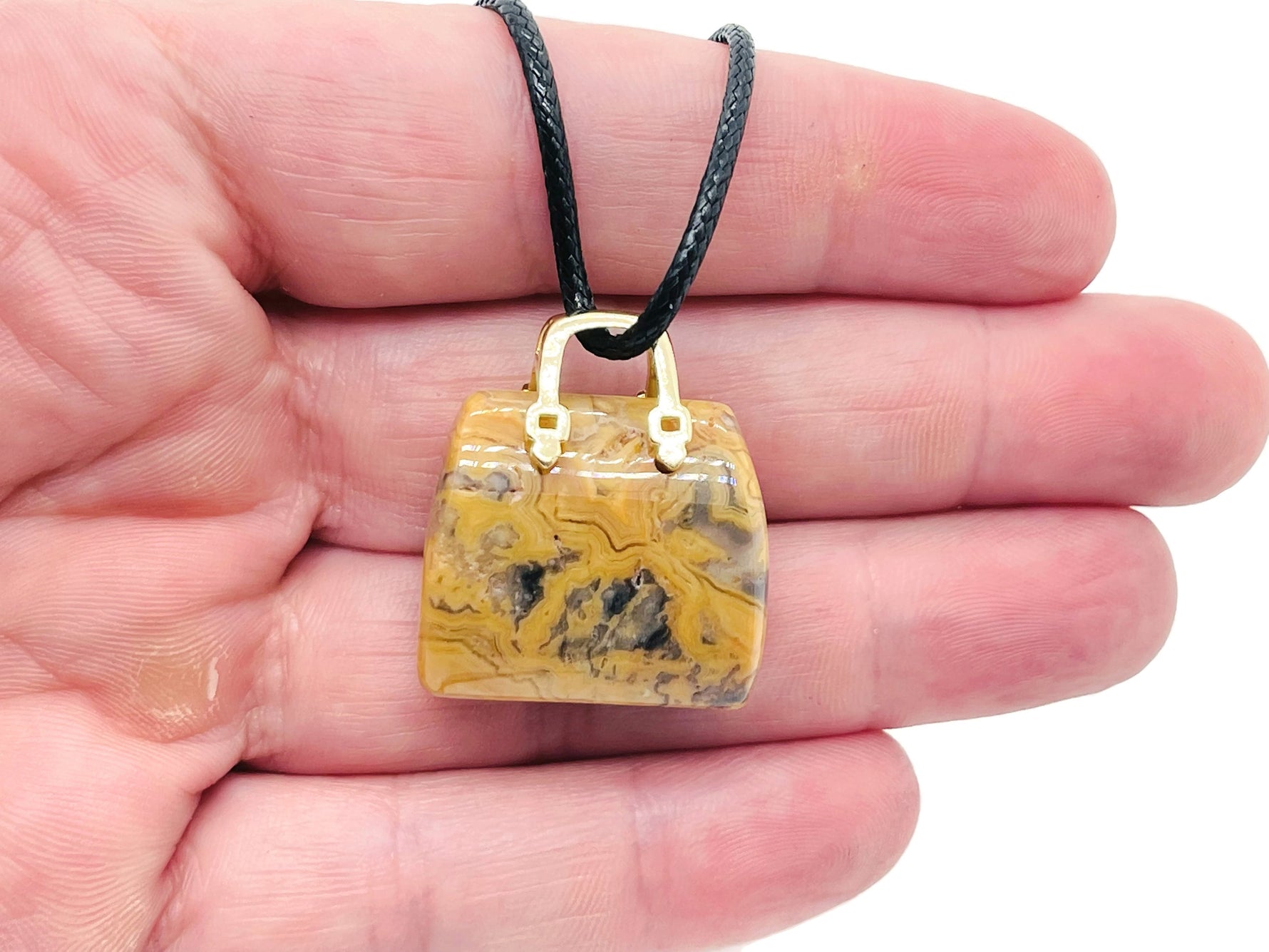 Crazy Lace Agate crystal carved as a purse-shaped gemstone pendant with intricate patterns, designed as a stylish handbag accessory.