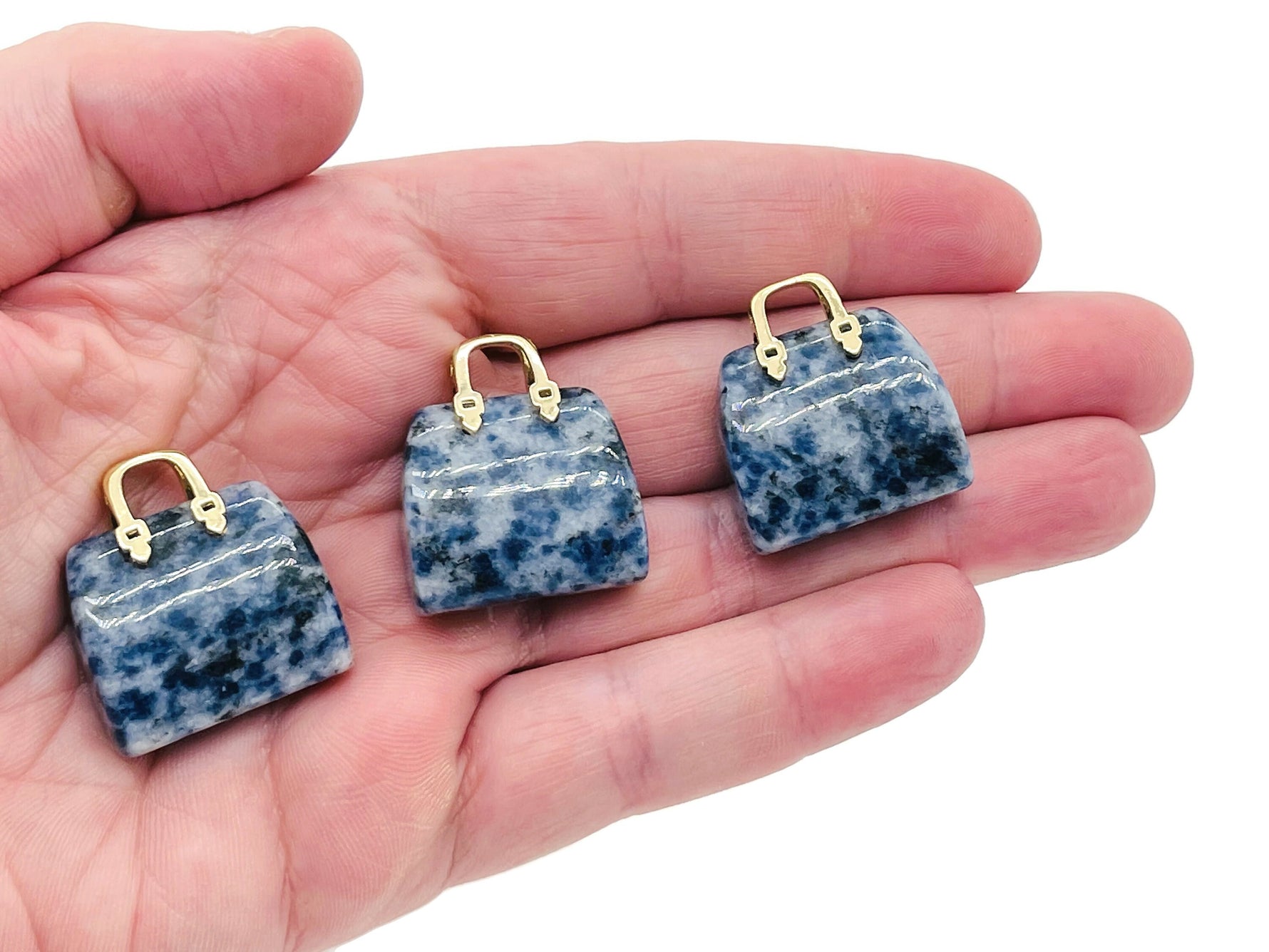Blue Spot Jasper crystal gemstone carving of a handbag pendant, showcasing intricate details and vibrant blue spots.