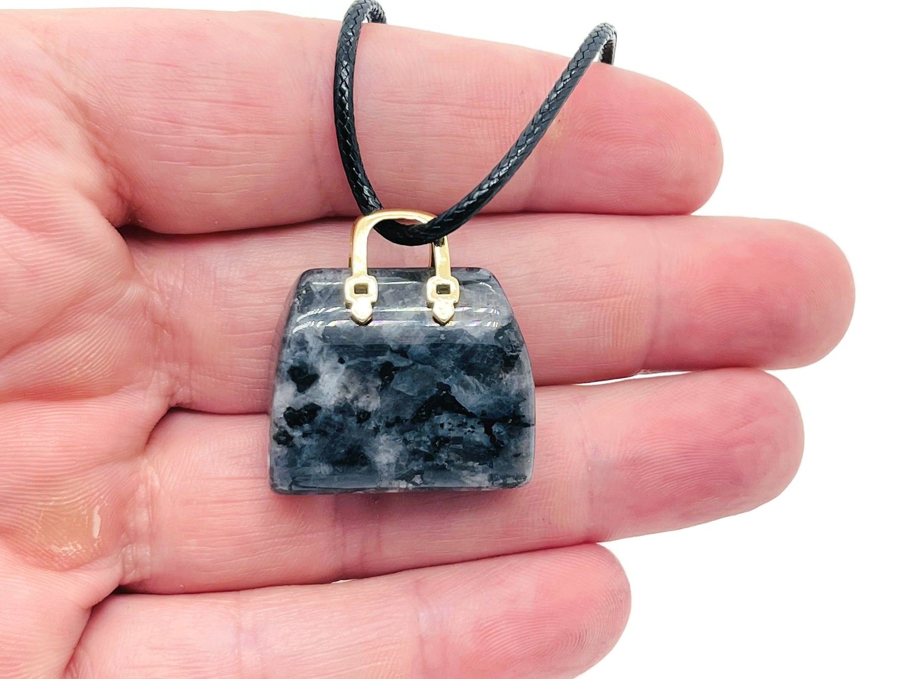 Larvikite crystal purse carving gemstone pendant with intricate handbag design, showcasing polished dark gray and blue hues.