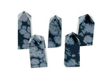 Snowflake Obsidian obelisk tower crystal from GemstoneGO, showcasing black stone with white snowflake-like patterns.