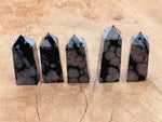 Snowflake Obsidian obelisk tower crystal from GemstoneGO, featuring black volcanic glass with white snowflake patterns and a polished finish.