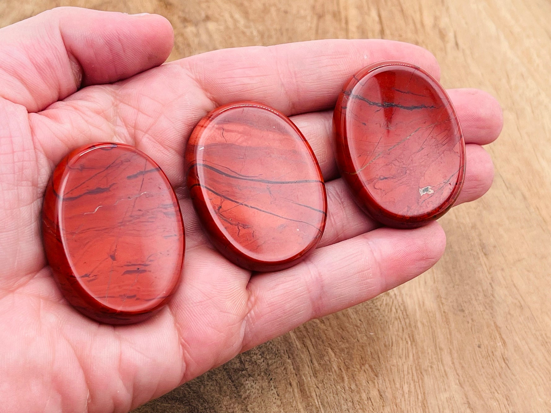 Red Jasper worry stone from GemstoneGO, a soothing 4.5x3.5cm crystal for stress relief, with polished, smooth surface.