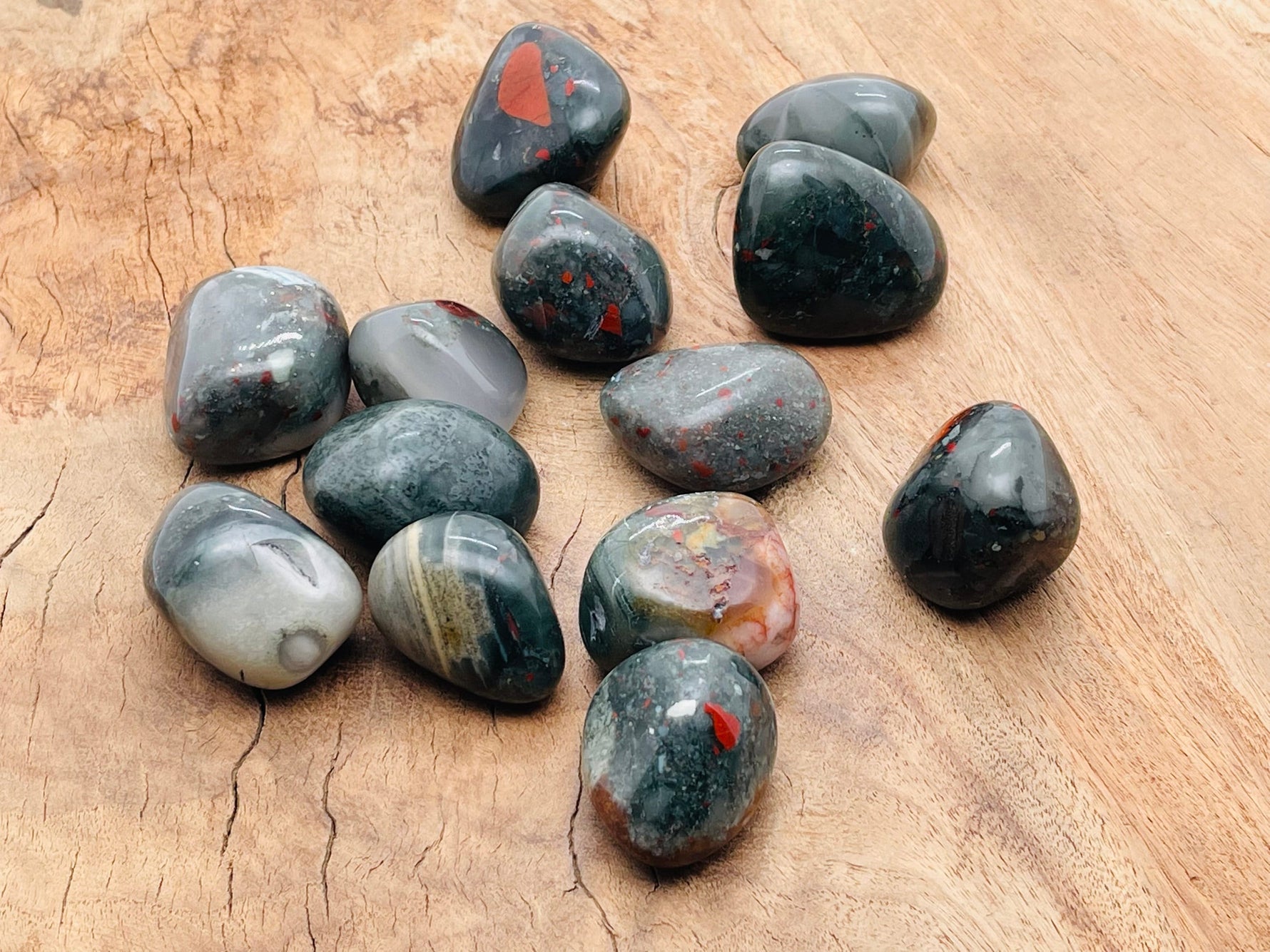 African Bloodstone tumbled stone from GemstoneGO, showcasing smooth, dark green and red mineral with natural patterns.