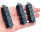 Lava volcanic obelisk tower crystal from GemstoneGO, showcasing deep red and black volcanic stone with a pointed top.