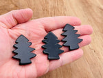 Handmade obsidian pine tree gemstone carving showing intricate tree details on a smooth black stone.