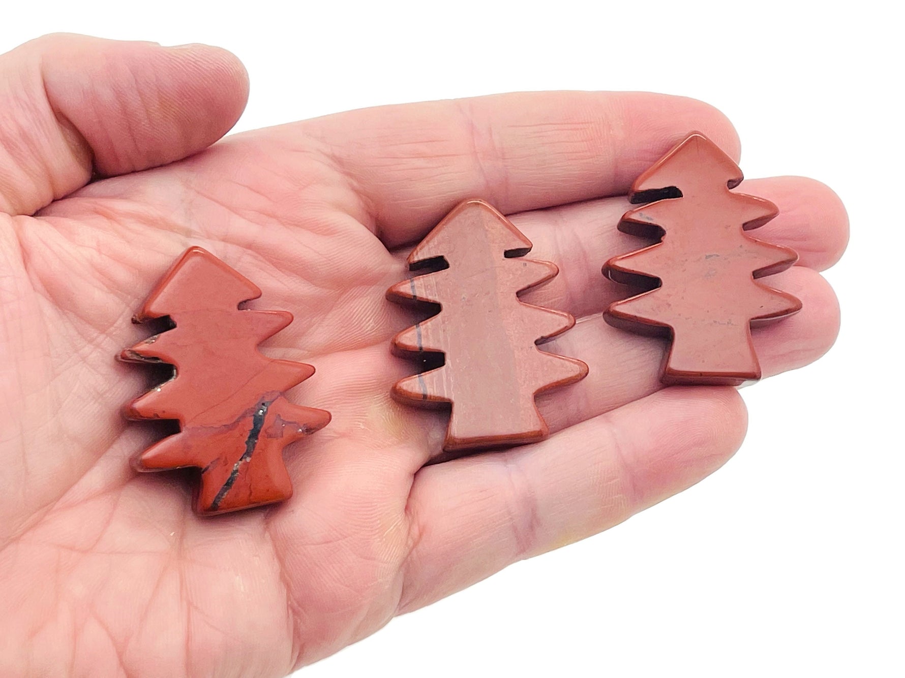 Handmade red jasper pine tree gemstone carving showing detailed tree shape on a polished stone from GemstoneGO.