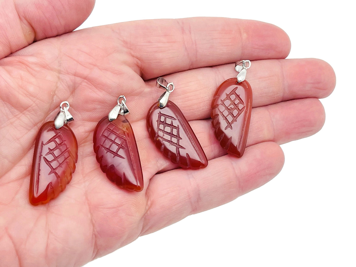 Carnelian angel wing crystal pendant with hole charm, featuring vibrant orange-red gemstone and detailed wing design.
