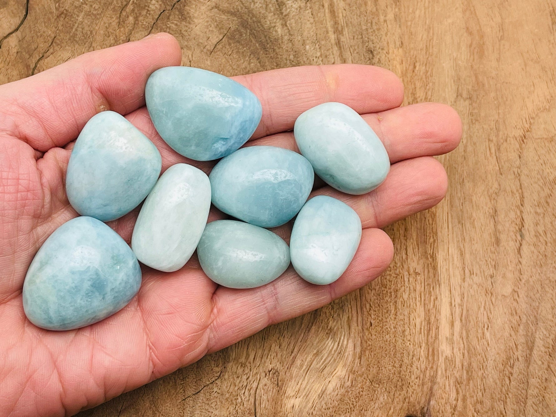 Smooth aquamarine tumbled stone from GemstoneGO, showcasing its light blue color and polished, rounded surface.