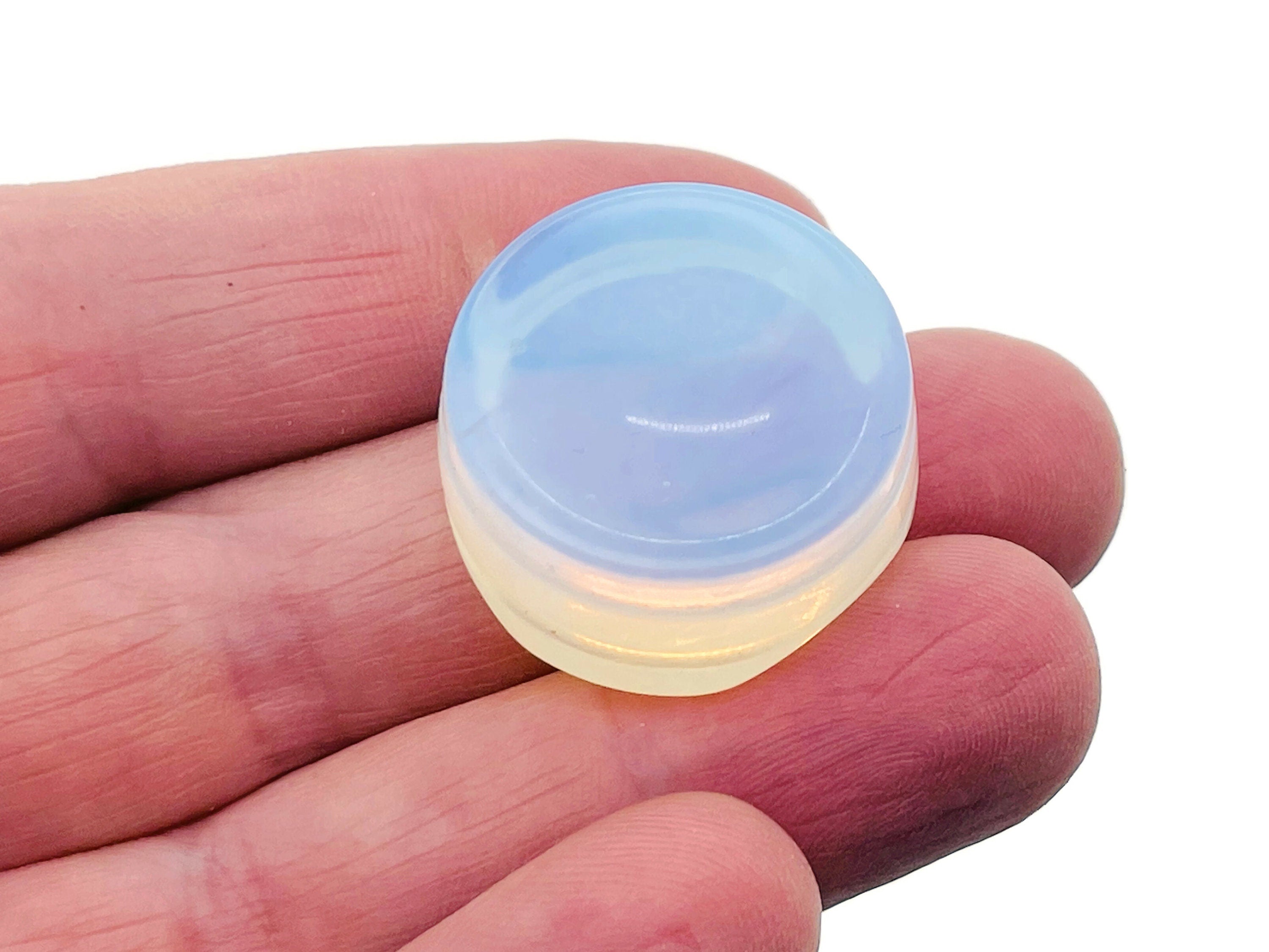 Opalite crystal sphere on carved gemstone stand, used for home decor and spiritual display, showcasing a smooth, luminous gemstone.