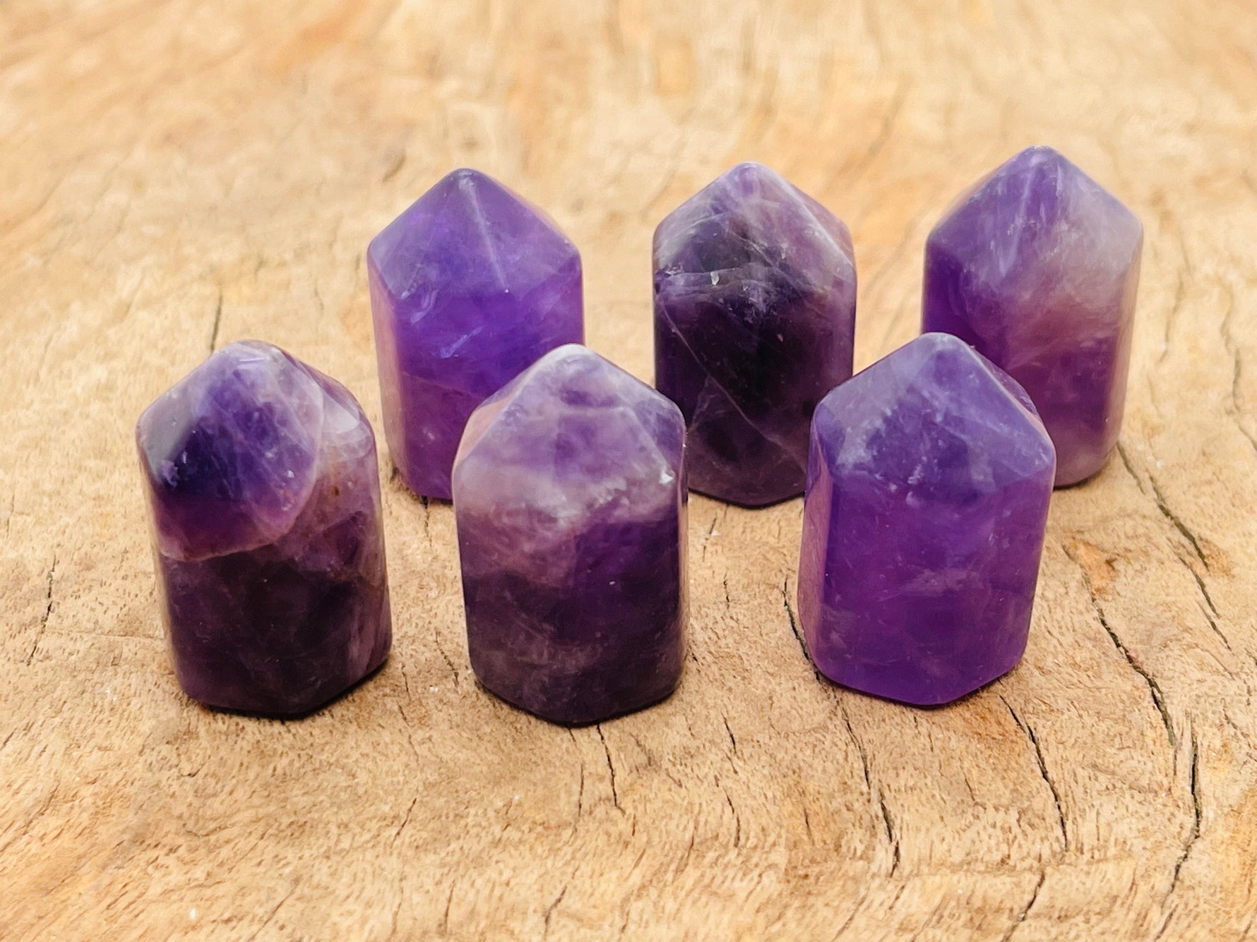 Amethyst obelisk tower crystal from GemstoneGO, 25mm tall, showcasing purple hues and polished facets on a plain background.