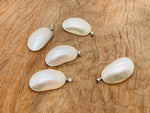 White natural pearl pendant from GemstoneGO, showcasing a delicate pearl with a silver setting on a jewelry-making display.