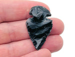 Black obsidian arrowhead carving gemstone with pointed tip and textured surface, displayed on a neutral background.