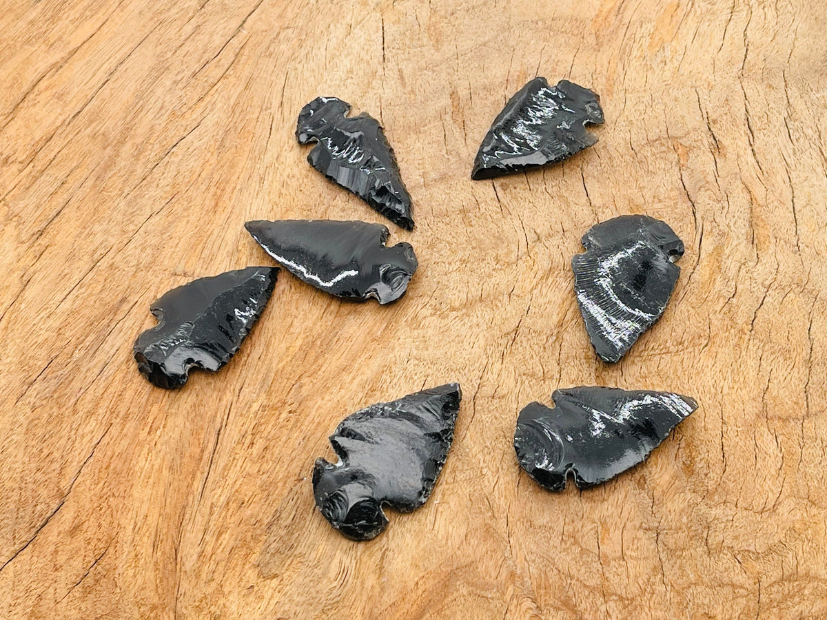 Black obsidian arrowhead carving gemstone with sharp tip and detailed texture, showcasing a natural black spearhead shape.