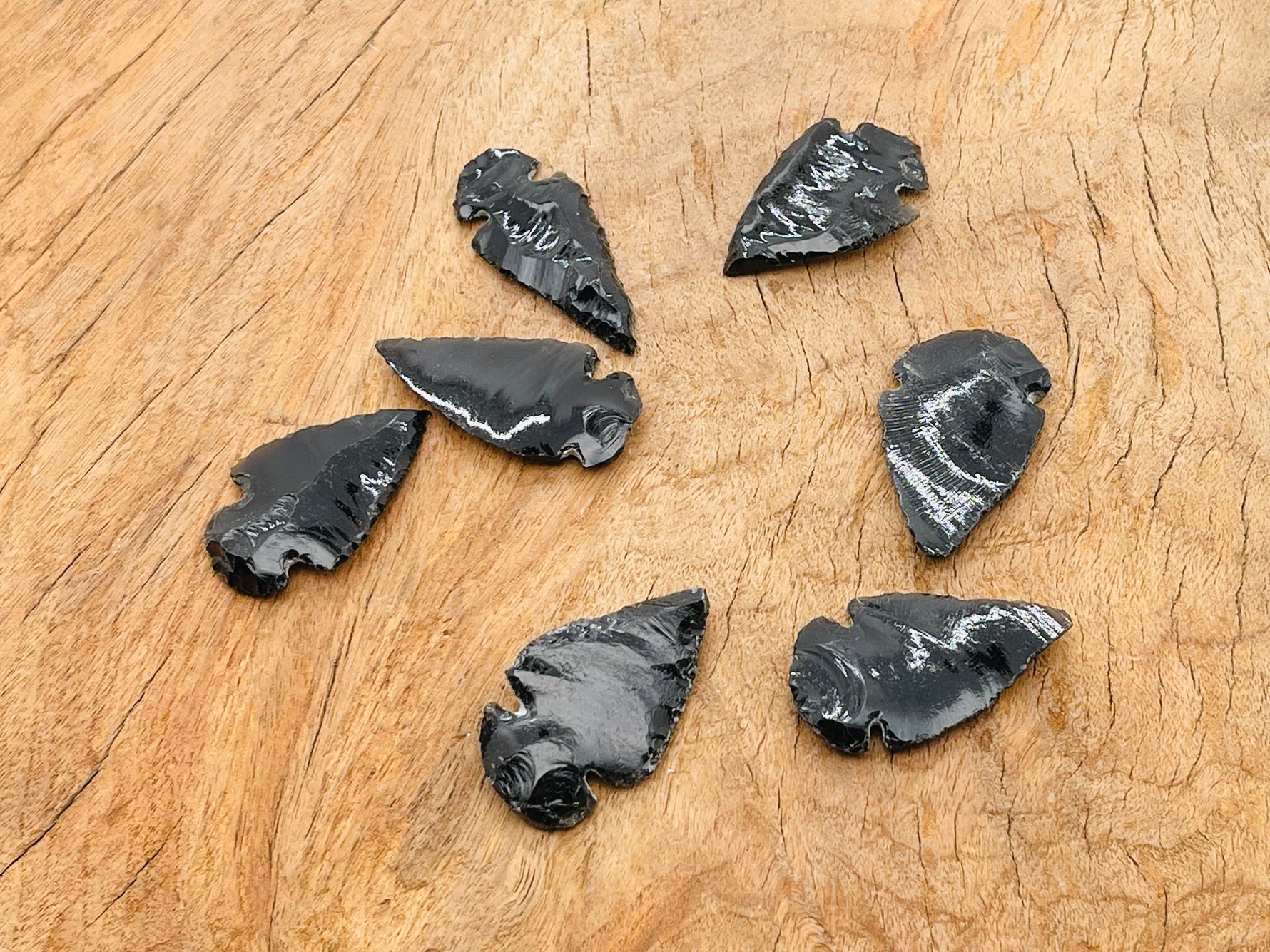 Black obsidian arrowhead carving gemstone with sharp tip and detailed texture, showcasing a natural black spearhead shape.