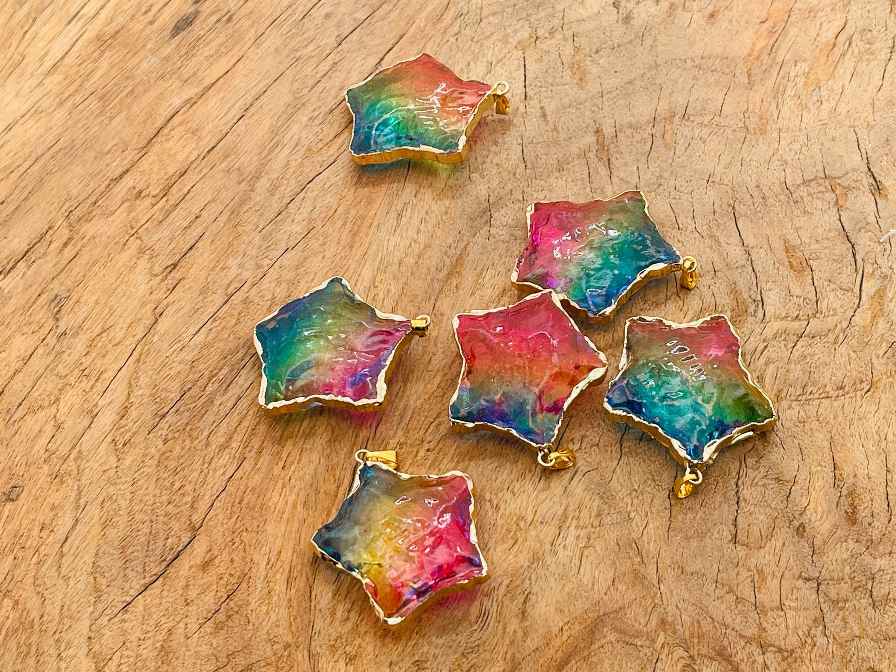 Pink, yellow, and blue rainbow aura star crystal pendant from GemstoneGO, featuring a loose, shimmering star-shaped gemstone.