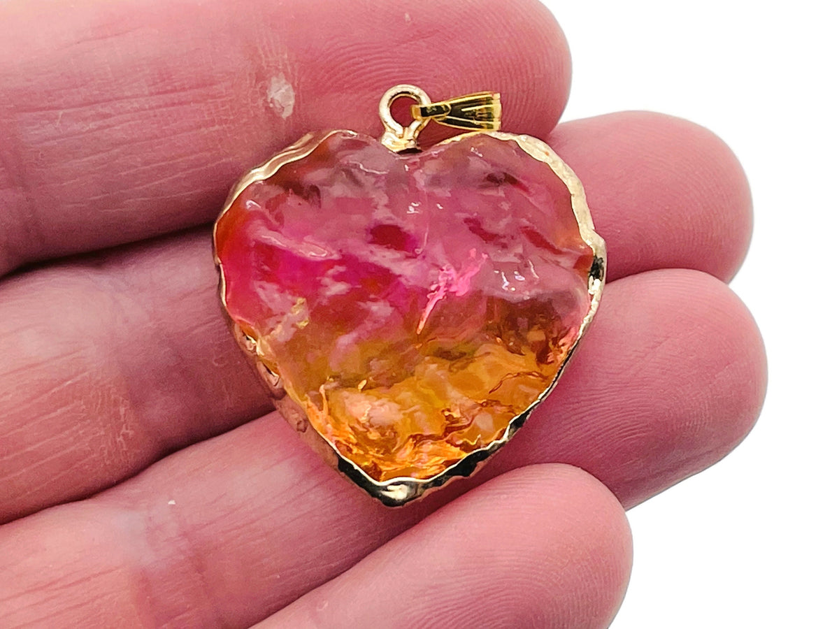 Pink and yellow rainbow aura heart crystal pendant from GemstoneGO, showcasing a loose, shimmering gemstone with vibrant rainbow colors.