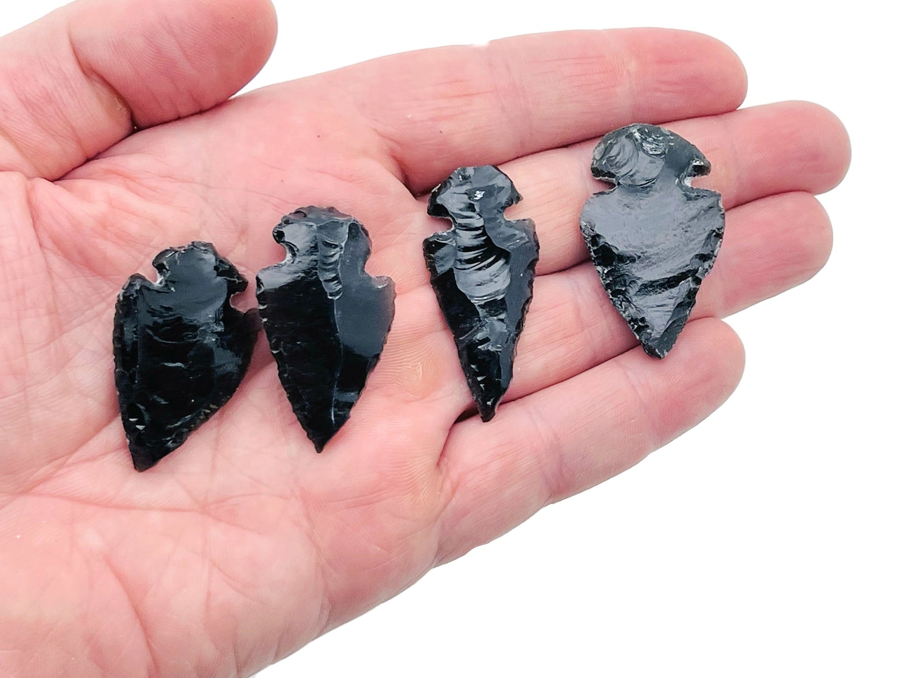 Black obsidian arrowhead carving gemstone with pointed tip and detailed texture, perfect for jewelry or collection.