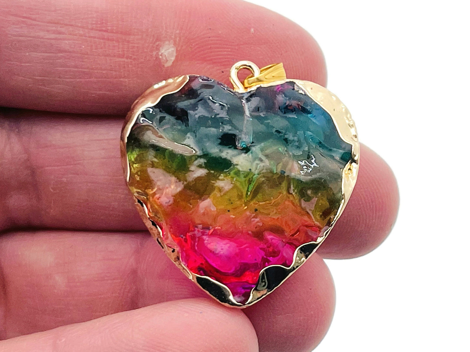 Pink, yellow, and blue rainbow aura heart crystal pendant by GemstoneGO, showcasing a vibrant, loose gemstone with a shimmering rainbow finish.