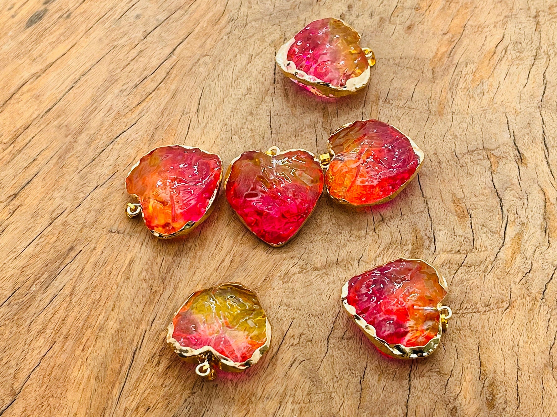 Pink and yellow Rainbow Aura Heart Crystal Pendant from GemstoneGO showcasing a vibrant, loose crystal with rainbow-colored aura coating.
