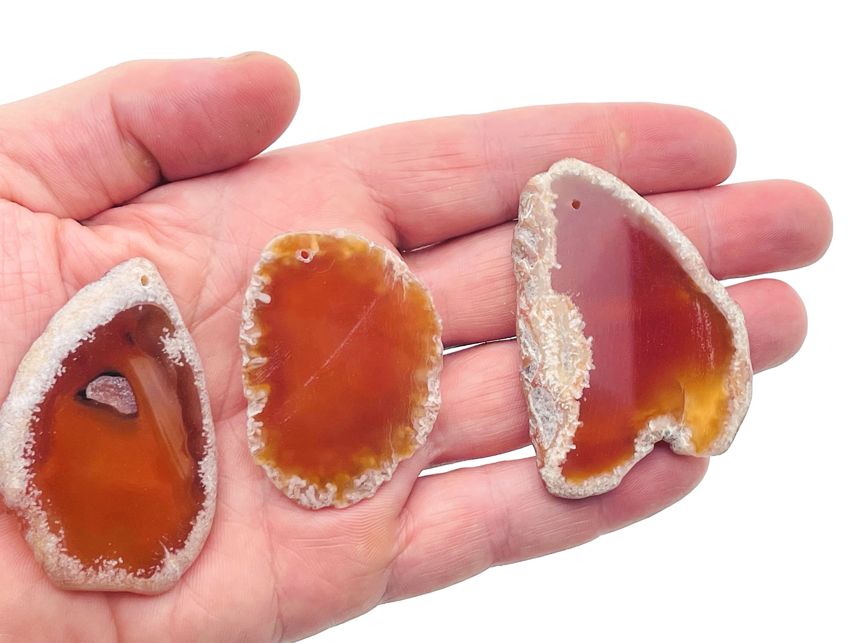 Red agate slice gemstone pendant with drilled hole, showcasing vibrant red and natural crystal formations.