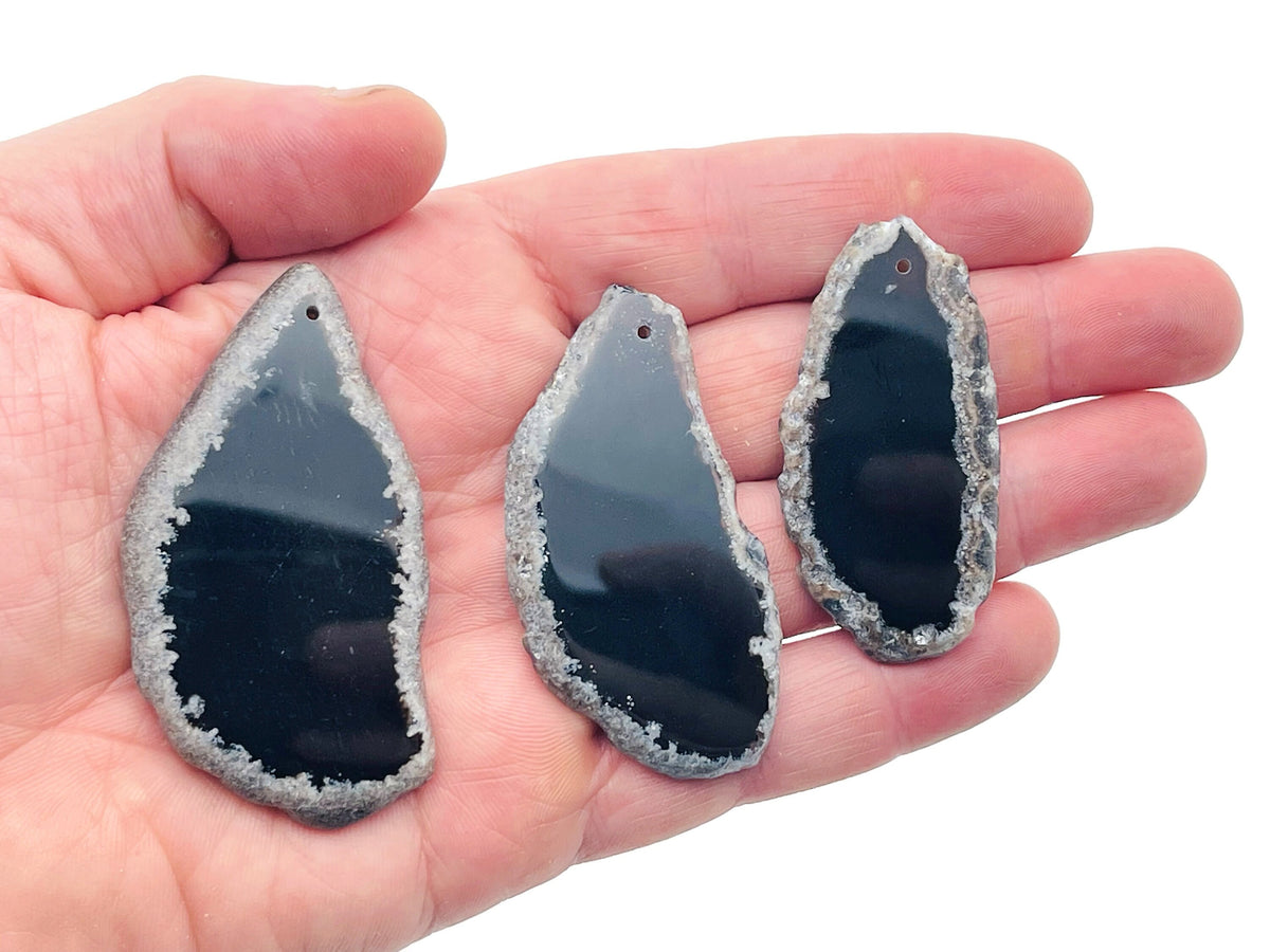Black Agate Slice drilled gemstone pendant with natural hole, showcasing polished black agate with layered, banded patterns for jewelry.