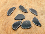 Black agate slice drilled pendant showing a smooth, polished black geode crystal with natural banding and a drilled hole for necklace use.