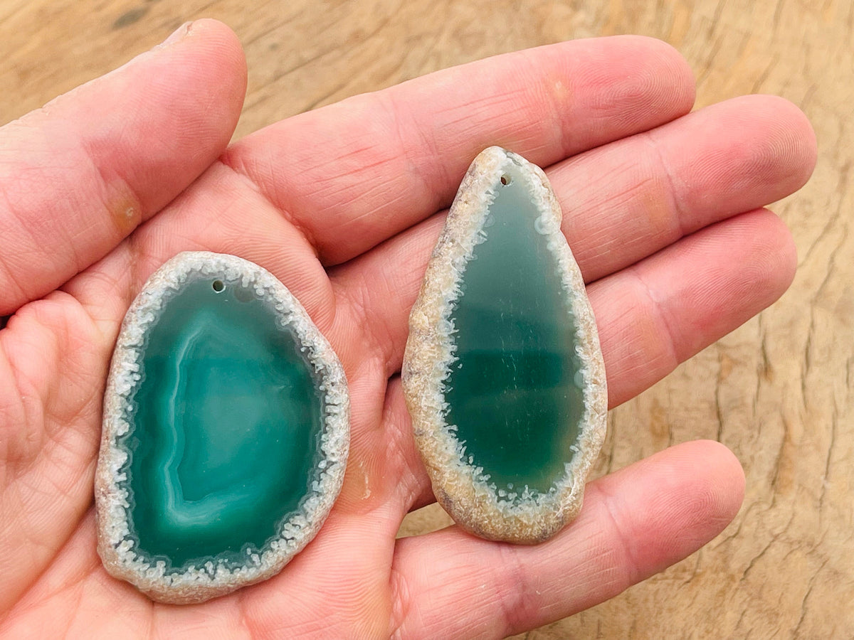 Green agate slice drilled for jewelry making, showcasing a natural geode crystal pendant with vibrant green tones.