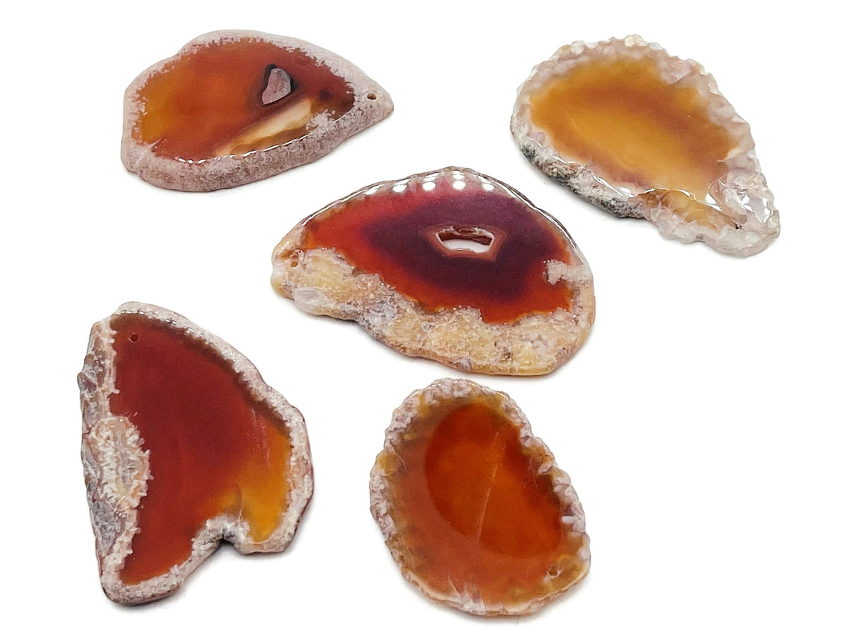 Red Agate Slice drilled gemstone pendant showing a vibrant red agate geode with natural banding and a drilled hole for jewelry.