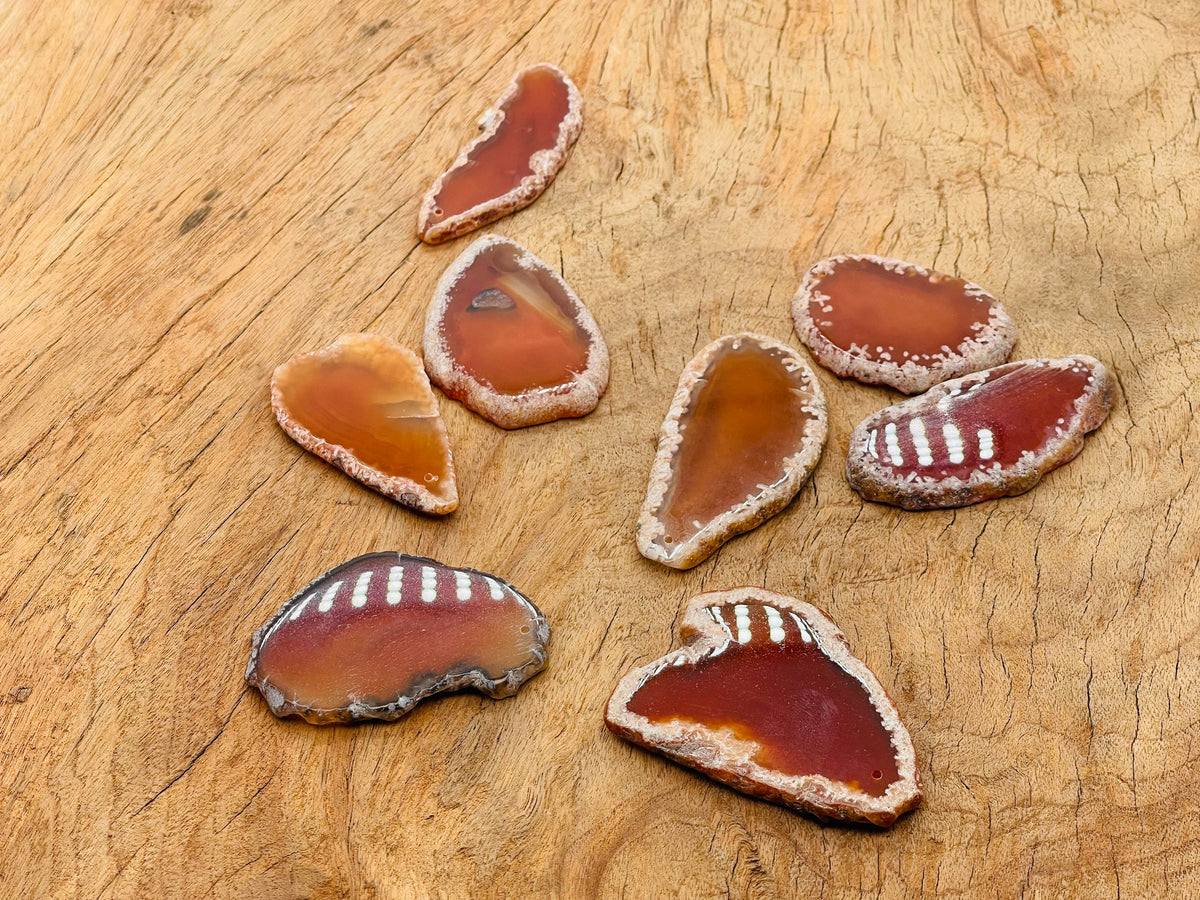 Red Agate slice drilled gemstone pendant showing a vibrant red agate geode with natural banding and a drilled hole for jewelry.
