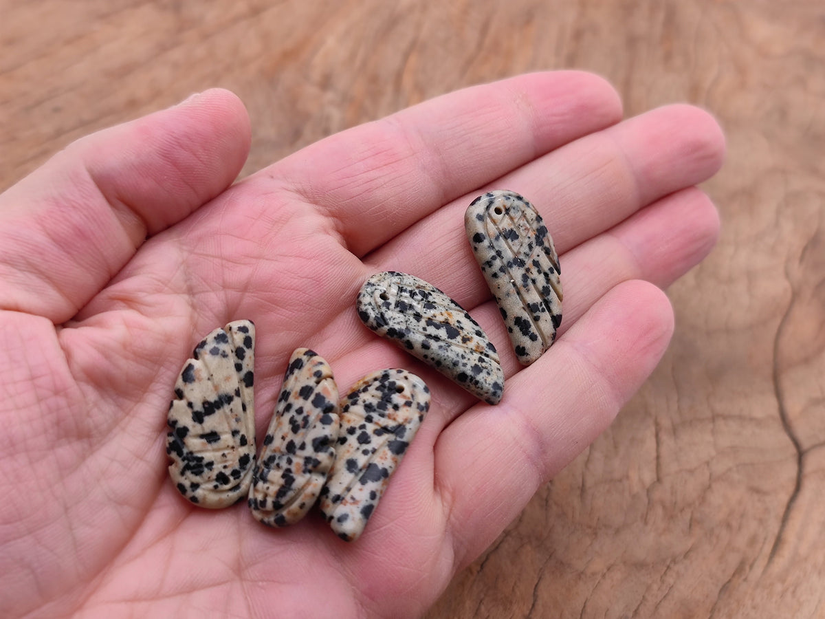 Dalmatian Jasper angel wing crystal pendant with hole charm, featuring black and beige spotted stone and detailed angel wing design.