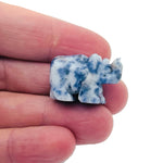 Handmade 30mm crystal gemstone rhino animal figure by GemstoneGO, carved with detailed features on a natural stone surface.