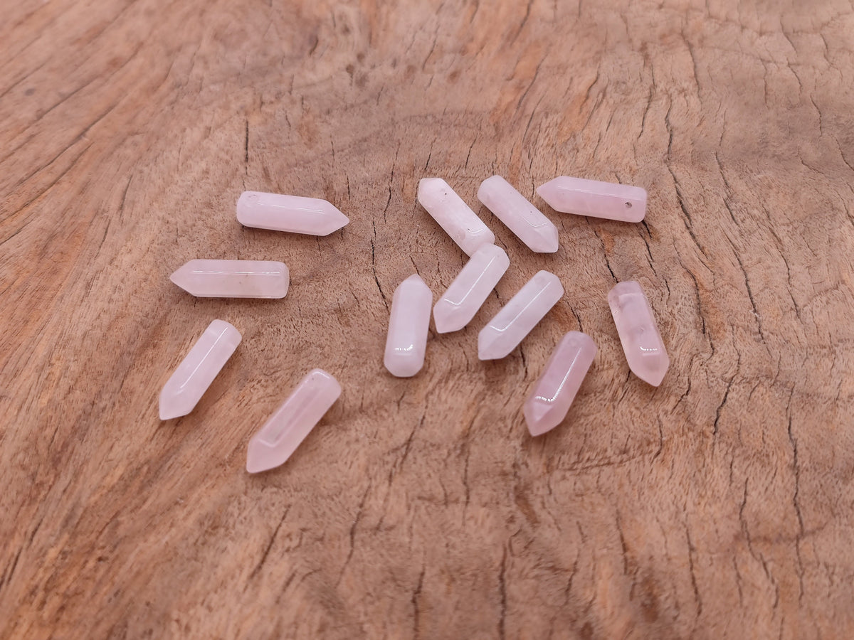 Rose quartz crystal point pendant with drilled hole from GemstoneGO, showcasing a polished pink gemstone with natural facets.