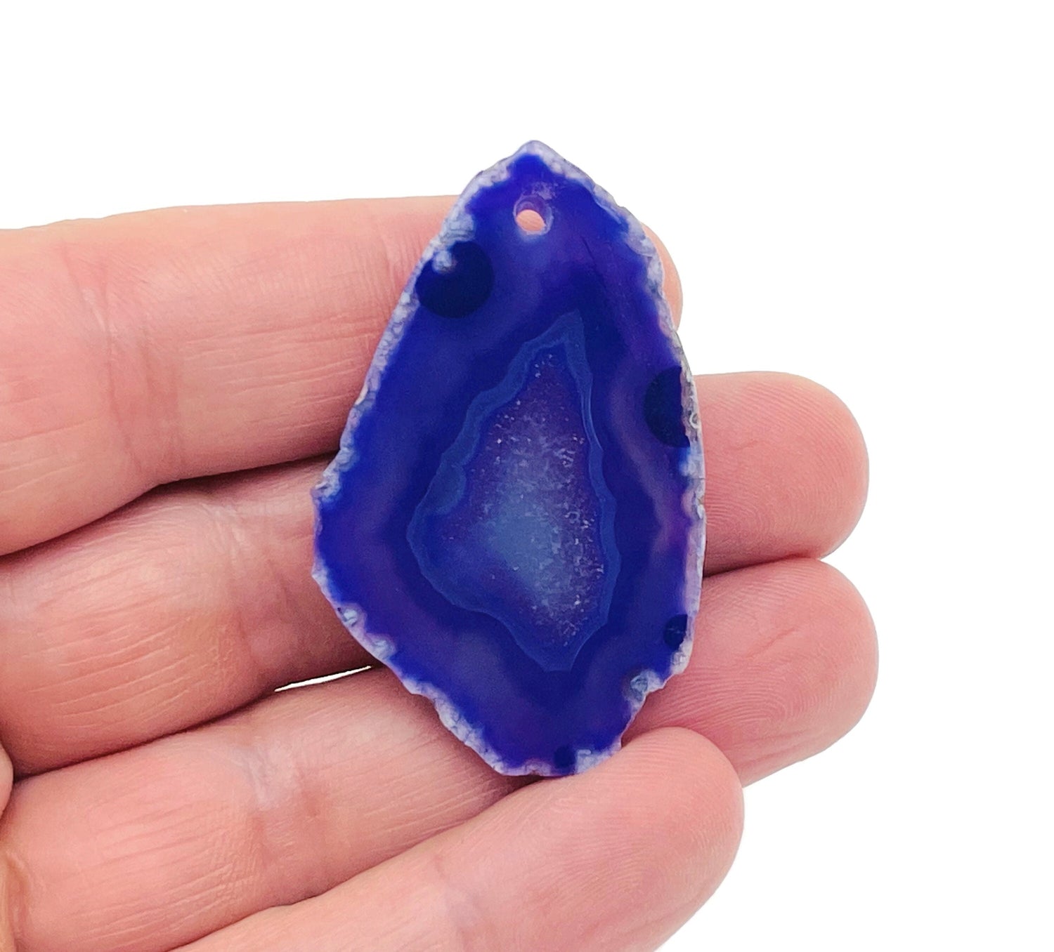 Purple agate slice drilled with hole, showcasing vibrant purple geode crystal pendant, gemstone jewelry piece from GemstoneGO.