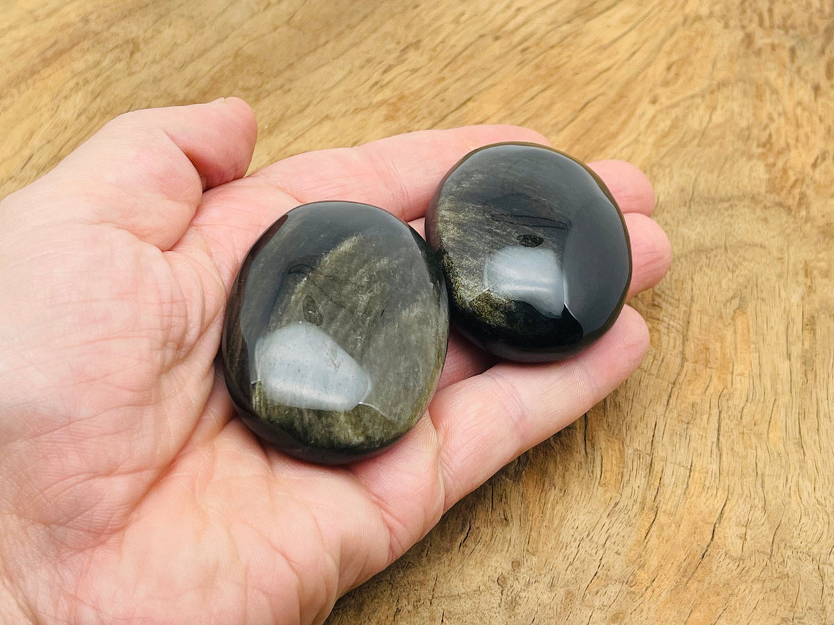 Golden sheen obsidian palm gemstone spa stone by GemstoneGO, showing smooth, polished black and gold-tinted volcanic stone.