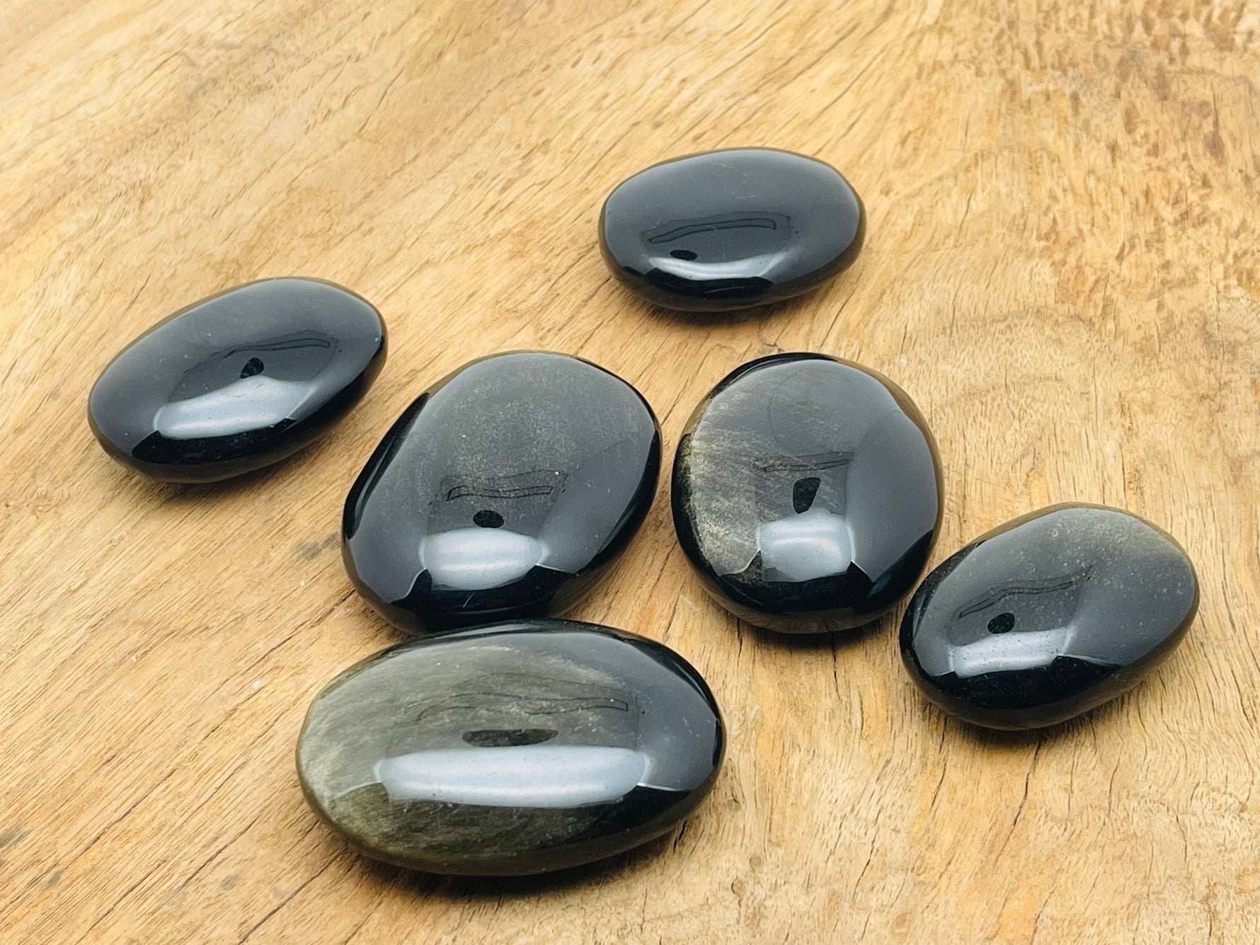 Golden sheen obsidian palm gemstone spa stone from GemstoneGO, showcasing a smooth, polished black and gold-toned healing stone.