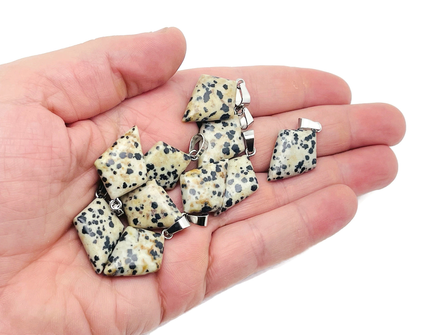 Dalmatian Jasper triangle pendant from GemstoneGO showing a geometric gemstone with distinctive black spots on a neutral background.
