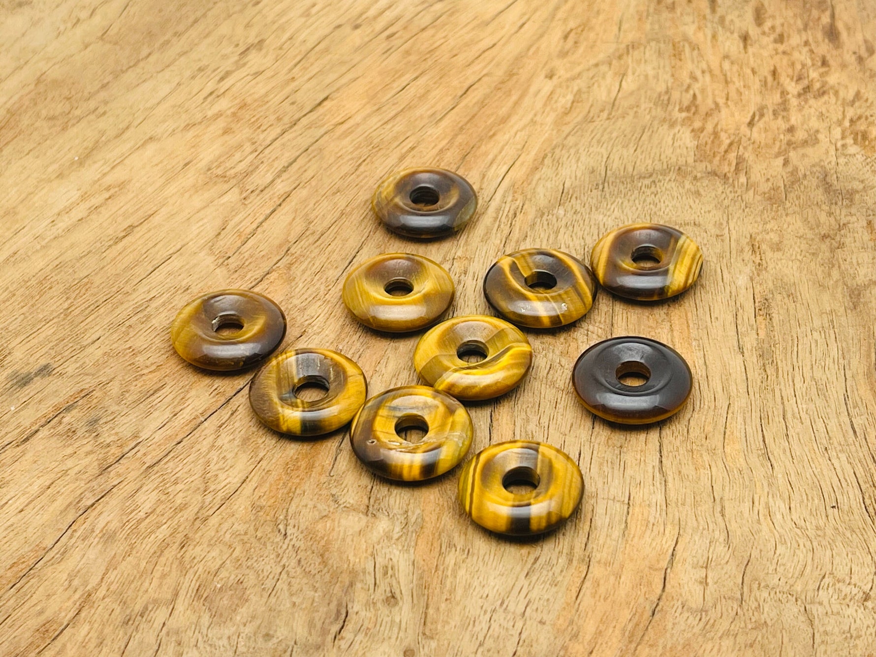 Tiger Eye crystal donut pendant, 20mm Pi stone from GemstoneGO, showcasing the smooth, polished gemstone with golden-brown bands.