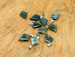 Moss agate triangle gemstone pendant from GemstoneGO featuring a geometric design and natural green and brown mineral patterns.