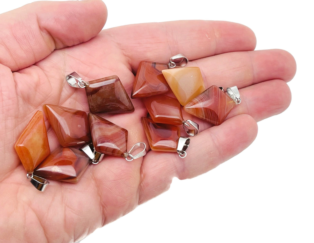 Carnelian triangle gemstone pendant from GemstoneGO featuring a geometric design and vibrant orange-red color.