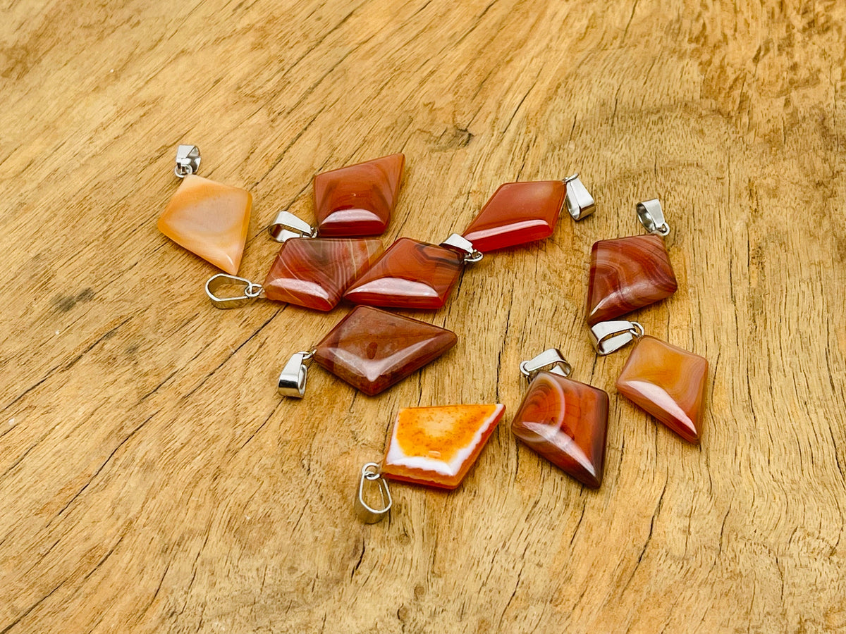Carnelian triangle gemstone pendant by GemstoneGO featuring a geometric design and polished orange-red stone.