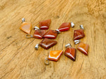 Carnelian triangle gemstone pendant by GemstoneGO featuring a geometric design and polished orange-red stone.